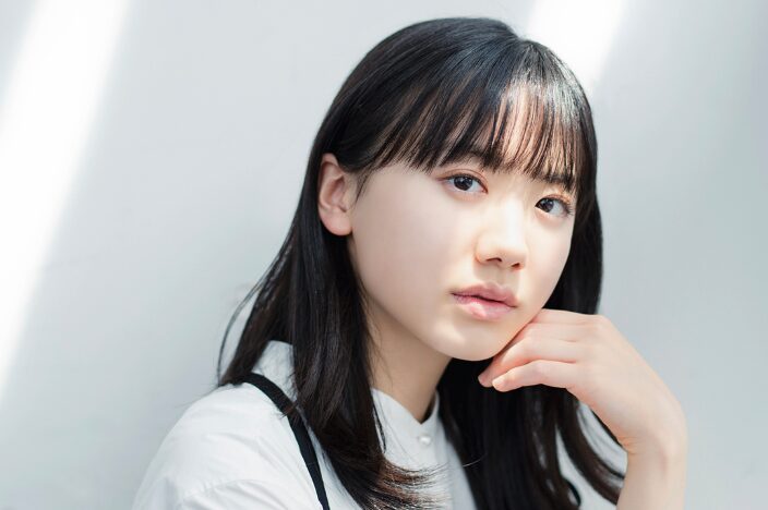 白背景で頬に手を添える芦田愛菜のバストアップポートレート（プロフィール用）