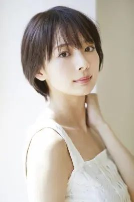 岡田紗佳のプロフィール用ポートレート画像。短い黒髪、白のトップ、そして左手を優しく首筋に添えたポーズ。自然光に照らされた明るい雰囲気で、カメラを穏やかに見つめている。