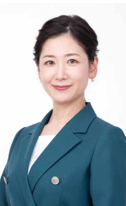 白背景の前で微笑む桑子真帆さんのプロフィール写真。青緑色のジャケットを着用。