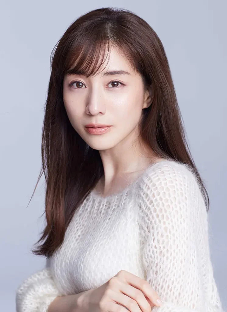 フラーム所属のフリーアナウンサー・女優、田中みな実さんの公式プロフィール写真（宣材写真）。白いニットを着用し、ライトグレーの背景の前で腕を組んで微笑むポートレート画像。